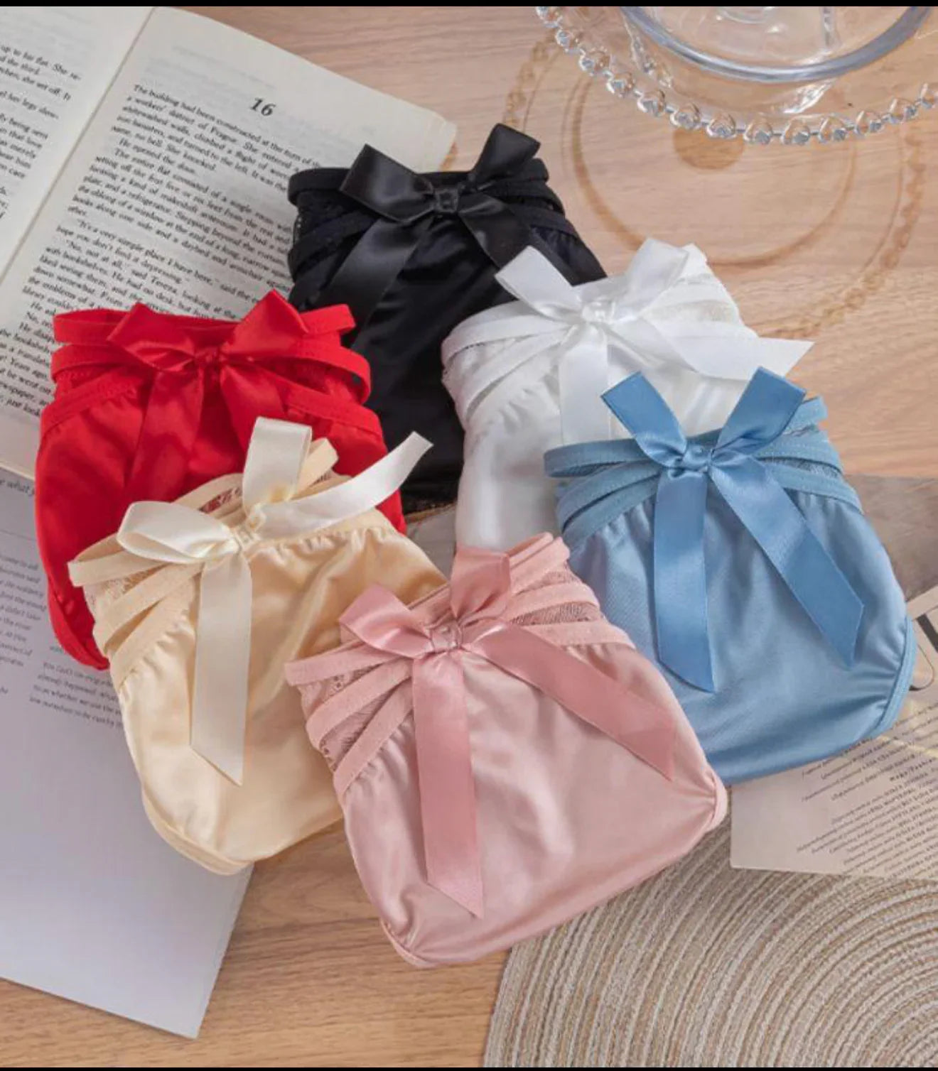 Assorted women’s panties in soft fabrics and pastel colors with bow details, arranged on a table.